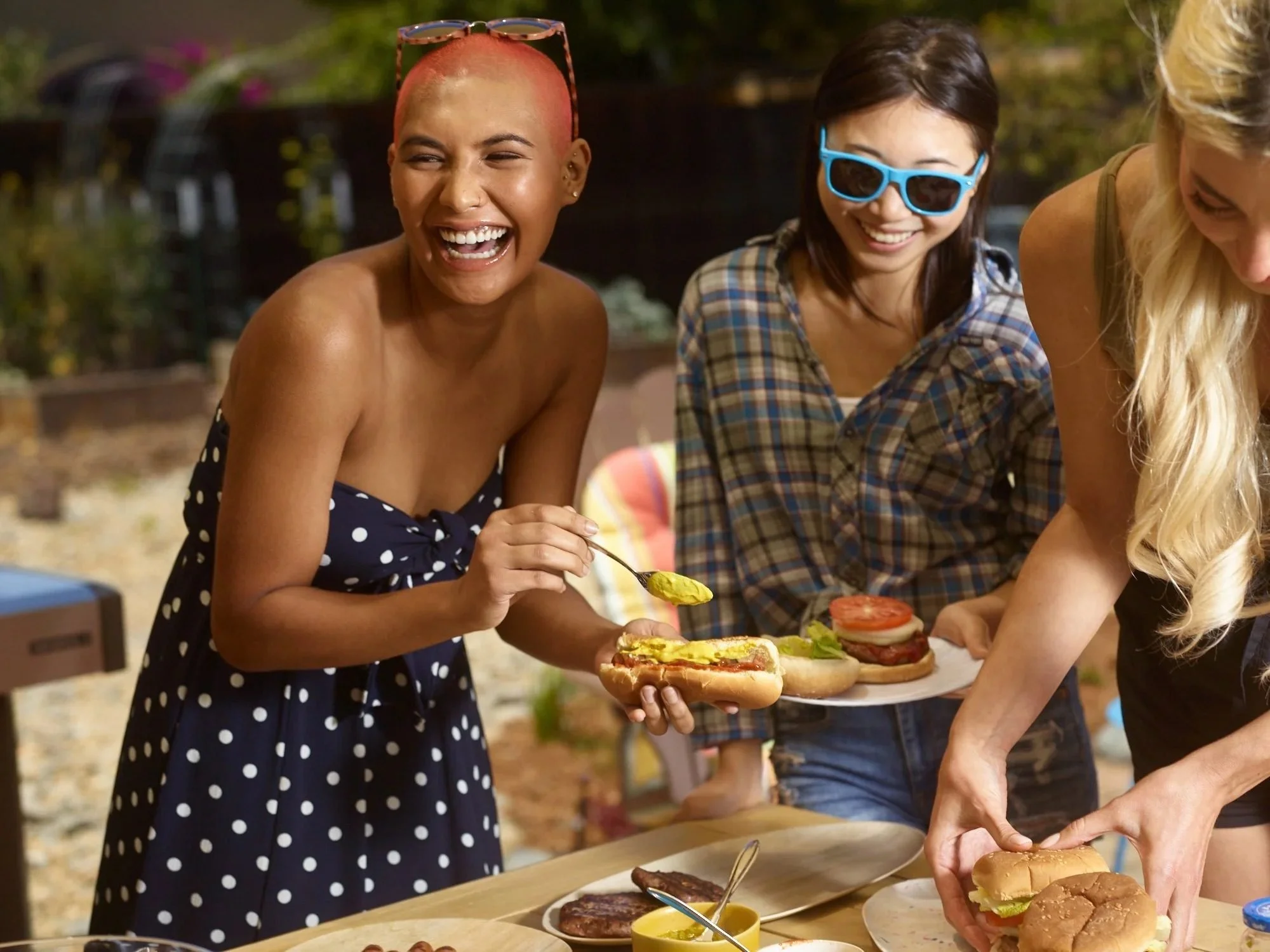 Friends laughing and serving burgers at an outdoor party, food lifestyle photography