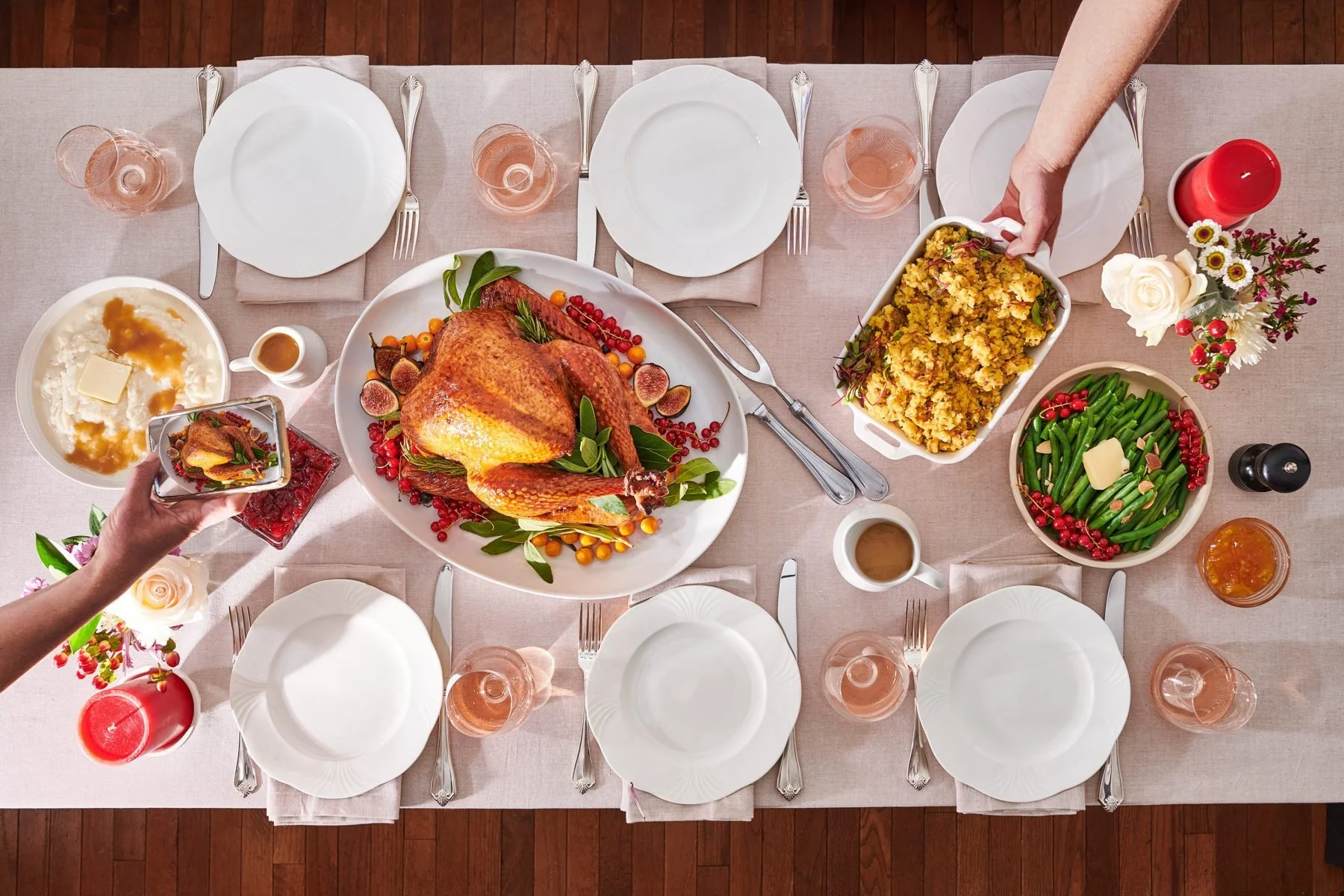 Overhead Thanksgiving table with hands serving dishes. Holiday lifestyle food photography.