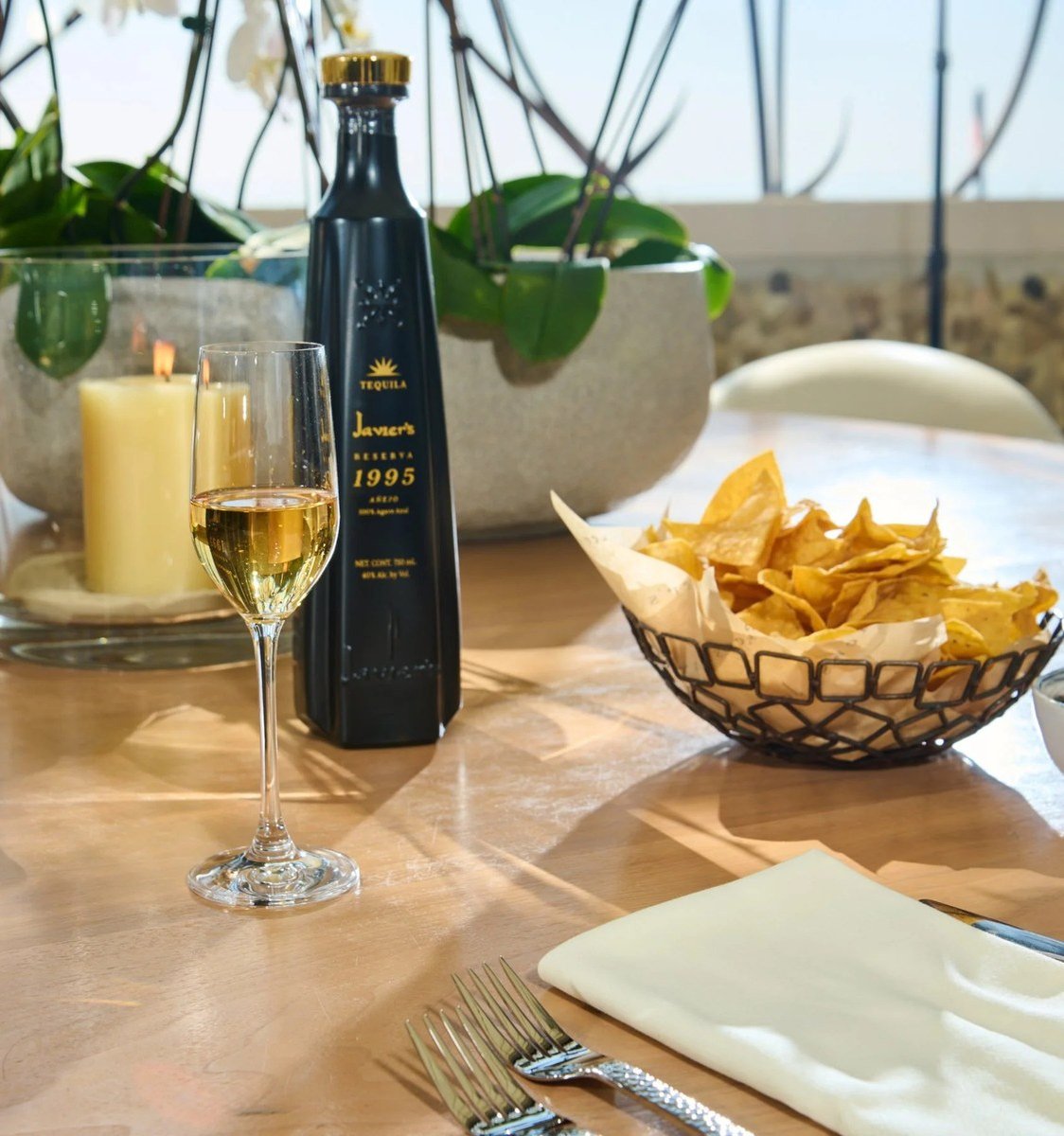 Tequila bottle with wine and chips on a restaurant table