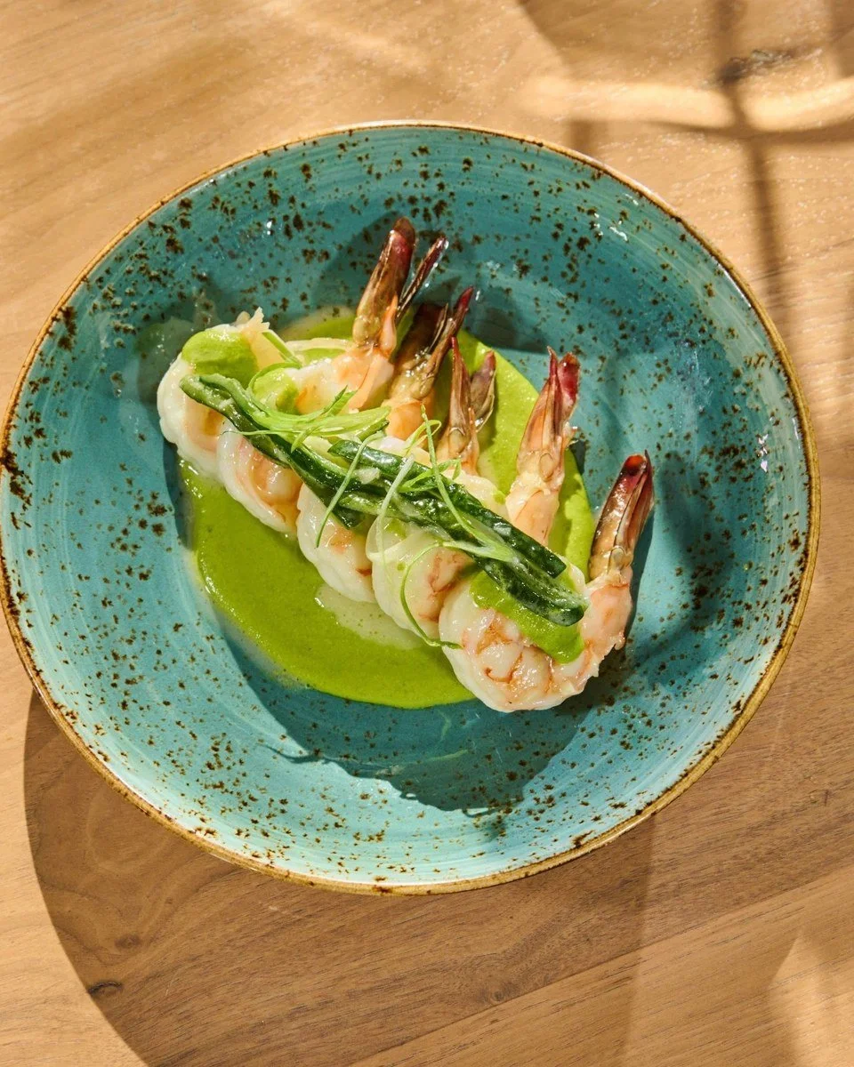 Shrimp on green sauce in a teal bowl