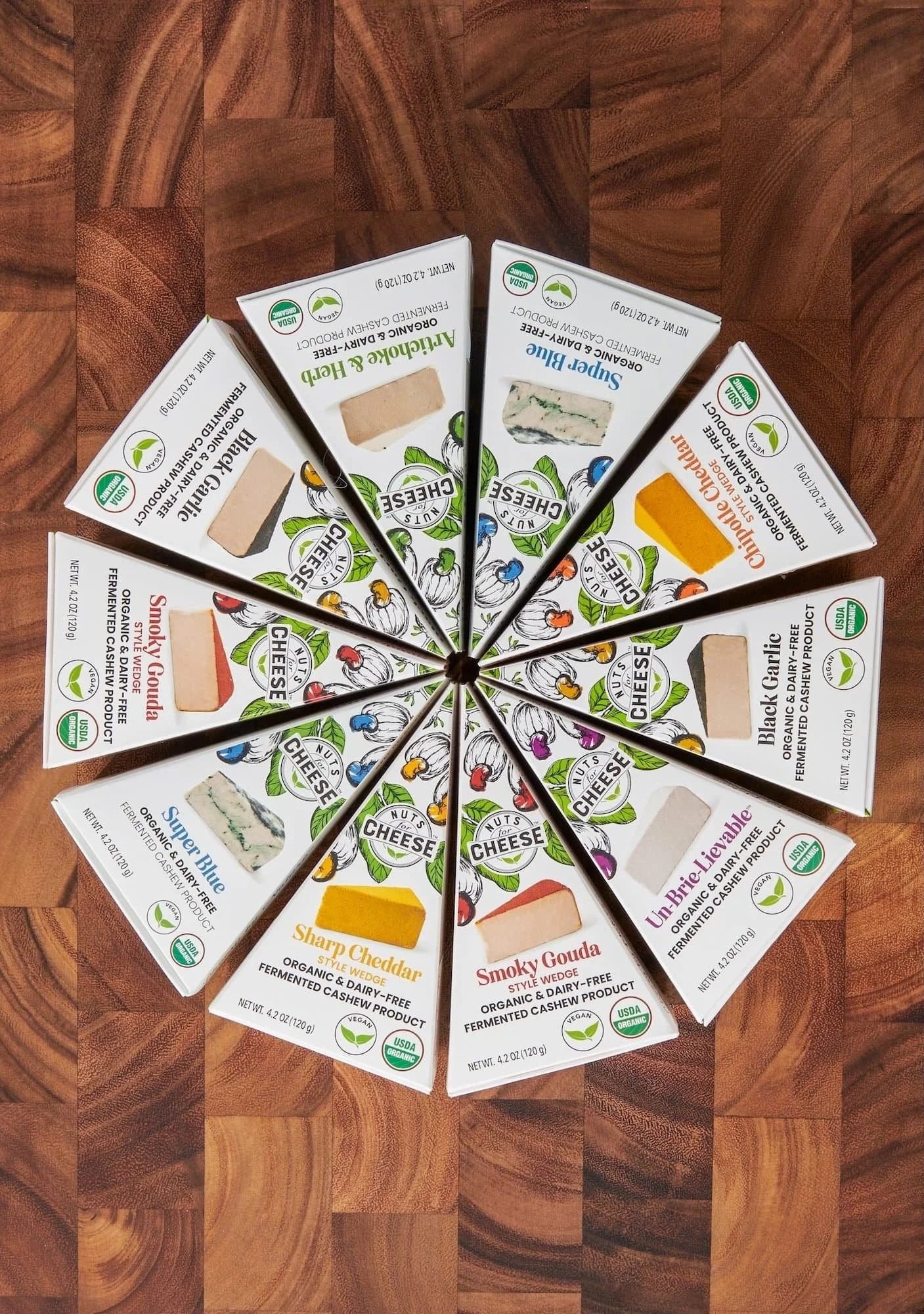 Cheese wedge packages arranged in a pinwheel on a wood board, CPG packaging photography
