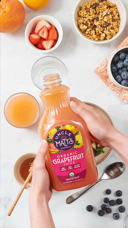 Hands pouring organic grapefruit juice at a breakfast table, beverage stop motion