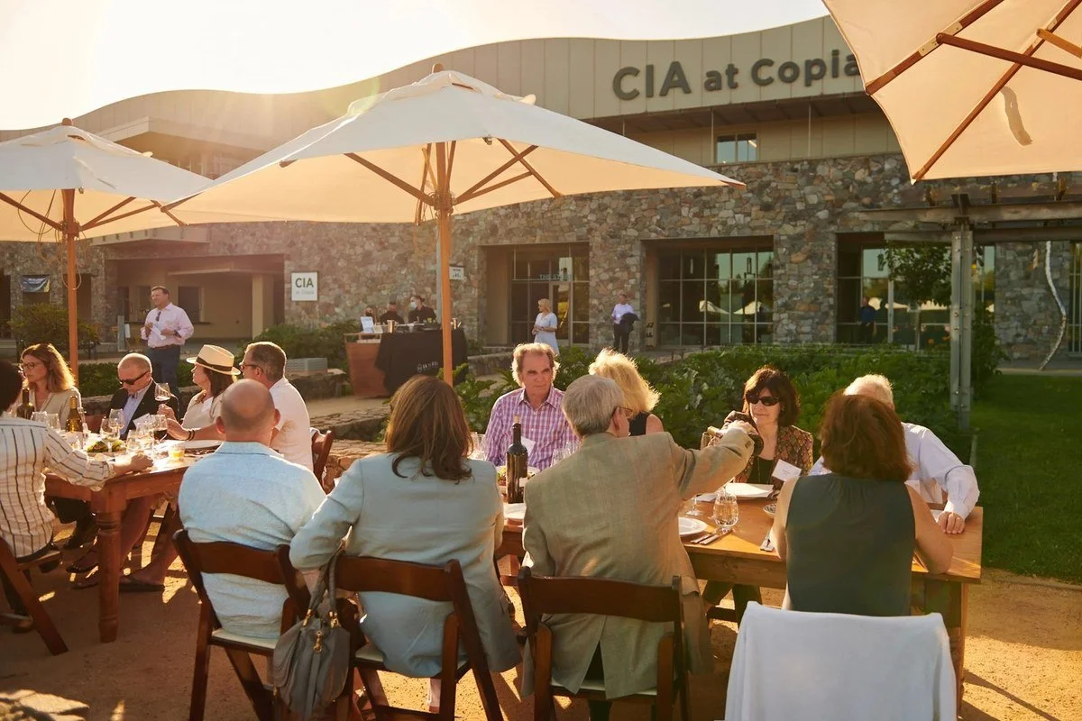 Guests dining under umbrellas on the restaurant patio at the CIA at Copia in Napa