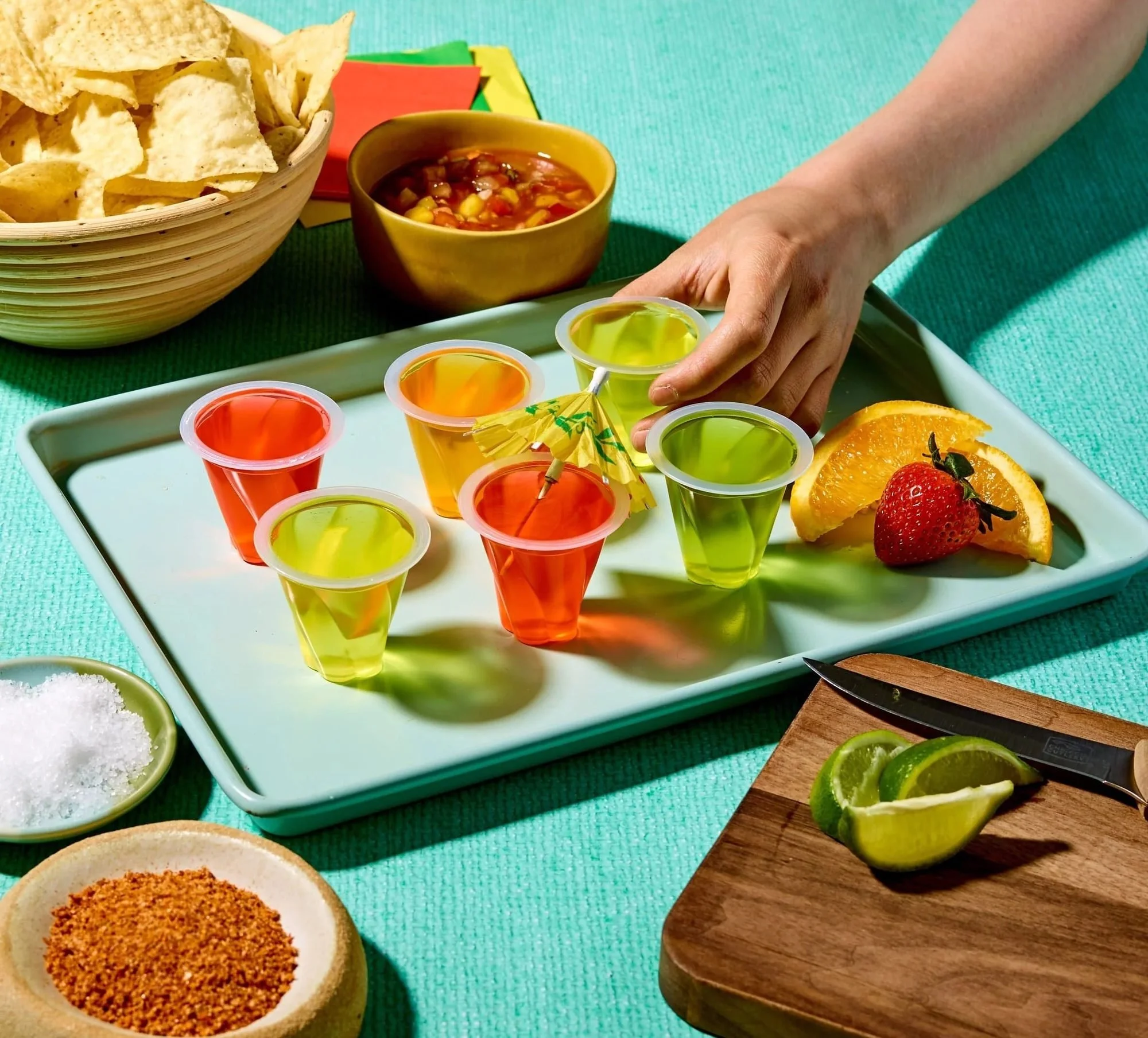 Hands picking up SLRRRP jelly cups from a tray with snacks, CPG snack photography
