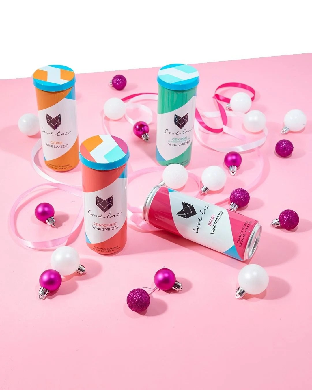 Sparkling cans with pink and white holiday ornaments, holiday CPG beverage photography