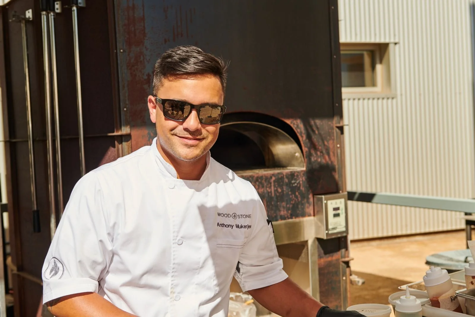 Chef in sunglasses at a wood-fired oven, chef portrait