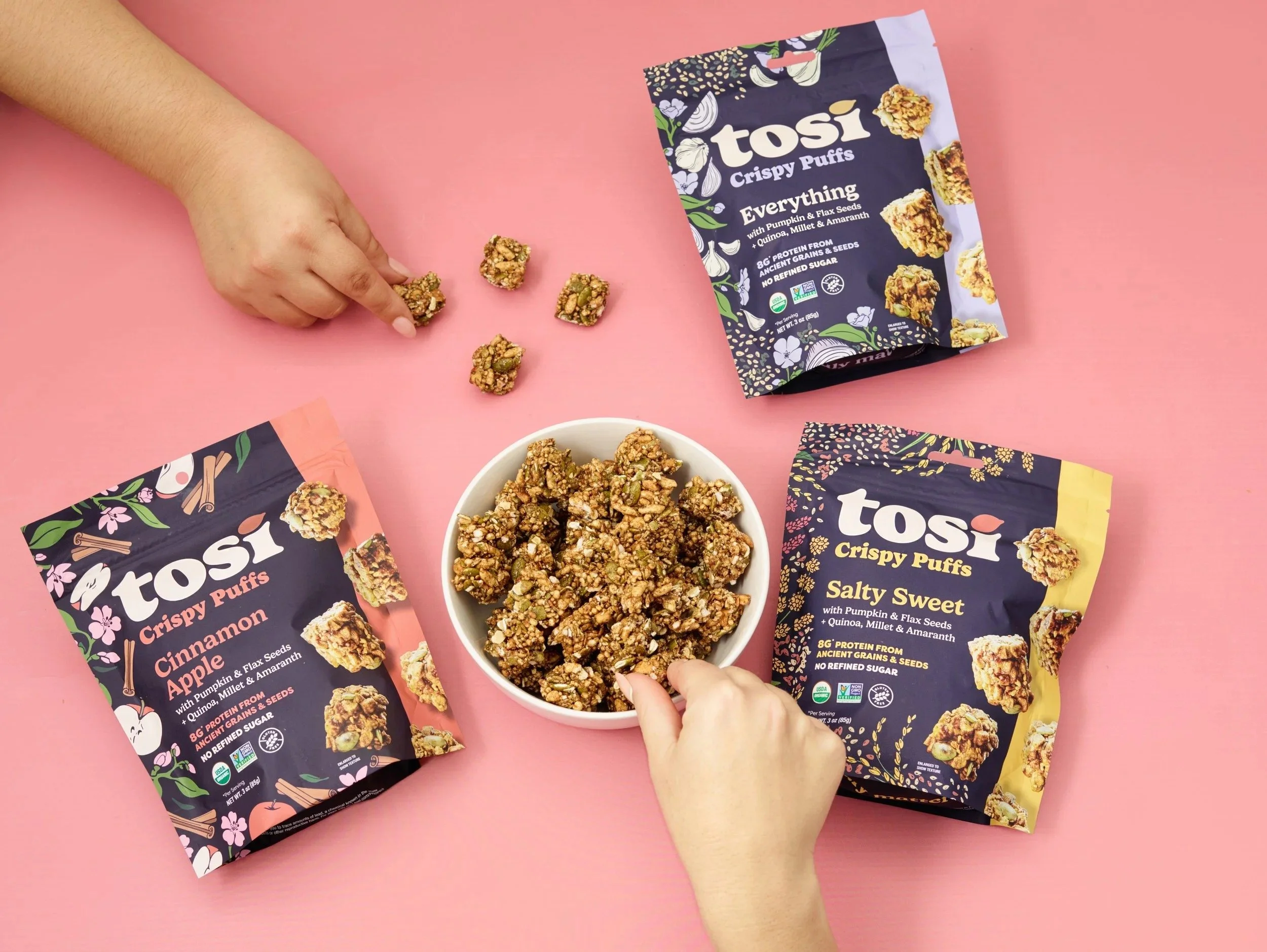 Hands reaching for Tosi snack bites and bags on pink, CPG lifestyle photography