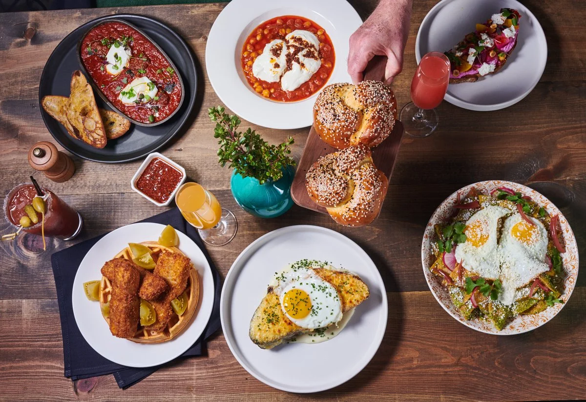 Overhead brunch spread of plated dishes on a wood table