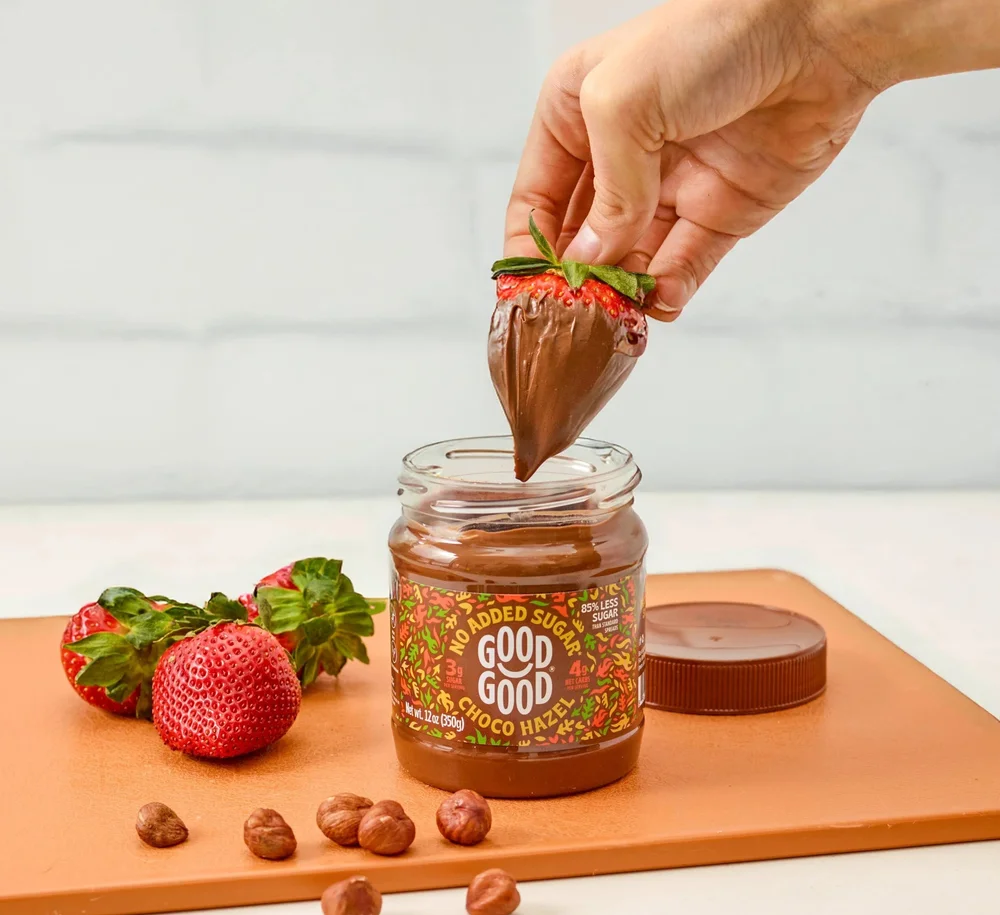 Strawberry dipped in Good Good chocolate hazelnut spread with hazelnuts, CPG photography