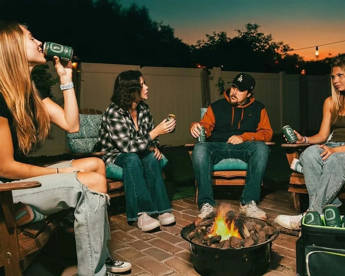 Friends drinking around a backyard firepit at night, beverage lifestyle photography