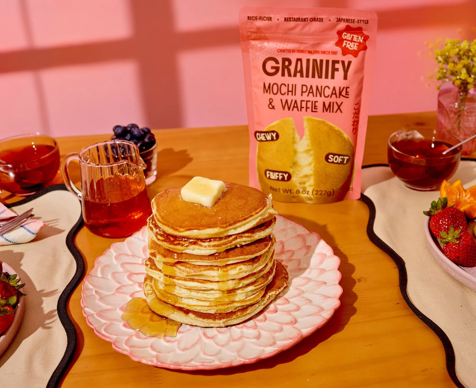 Stack of Grainify mochi pancakes with butter on a pink breakfast table. CPG food photography for packaged breakfast brands.