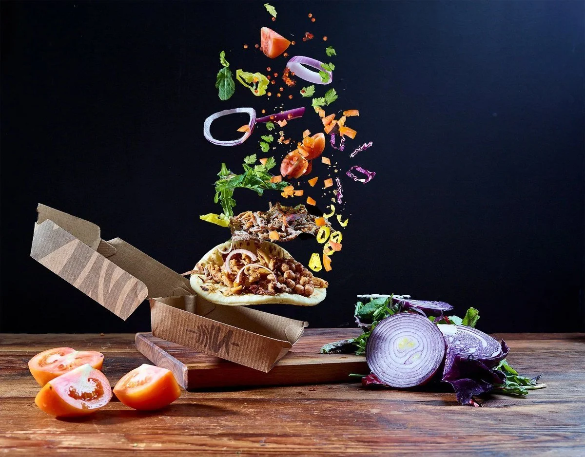 Gyro ingredients floating above a takeout box for a restaurant delivery menu