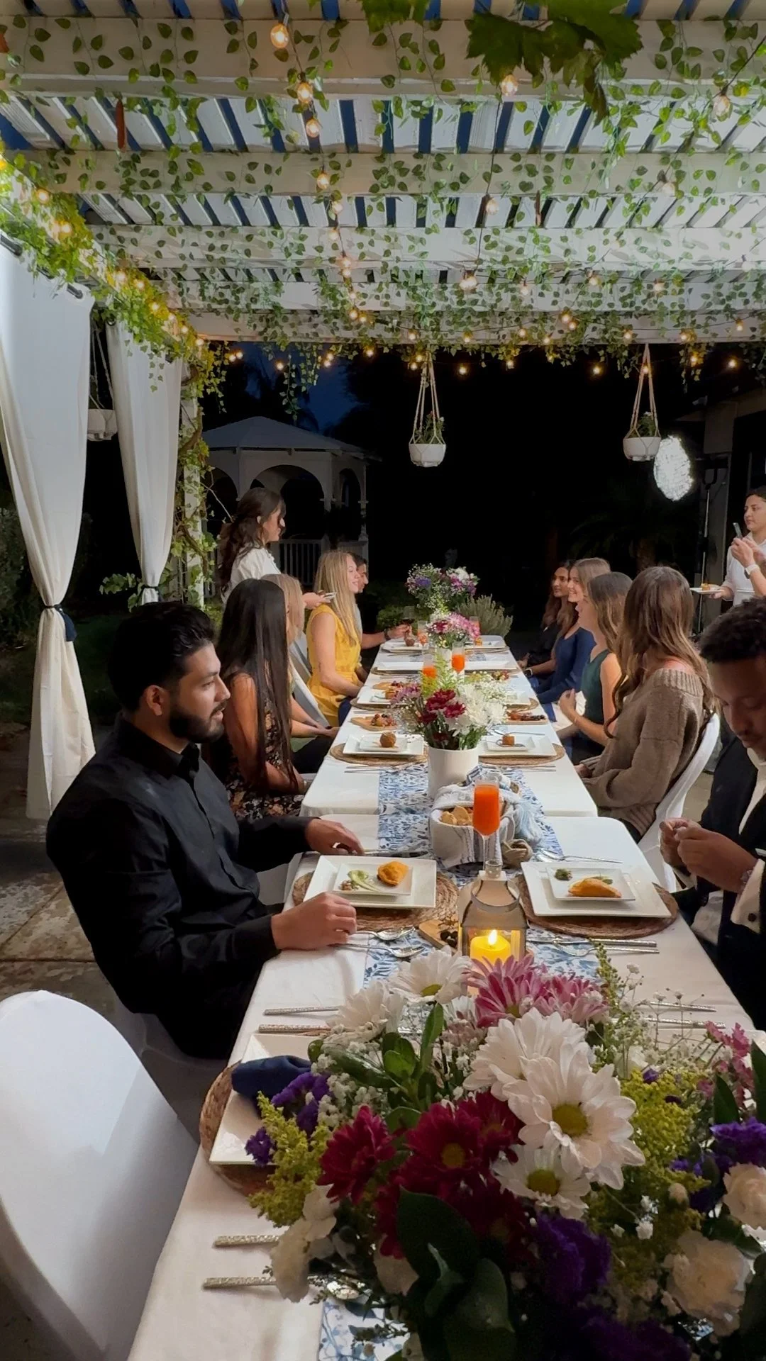 Guests gathered around the Casa Sarria dinner table under string lights in warm evening light