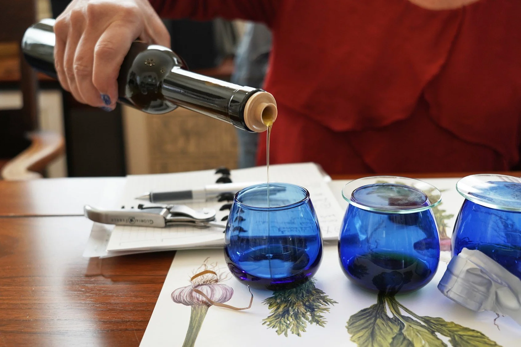 Olive oil pouring into blue tasting glasses at a professional olive oil tasting, editorial photography by Judy Doherty