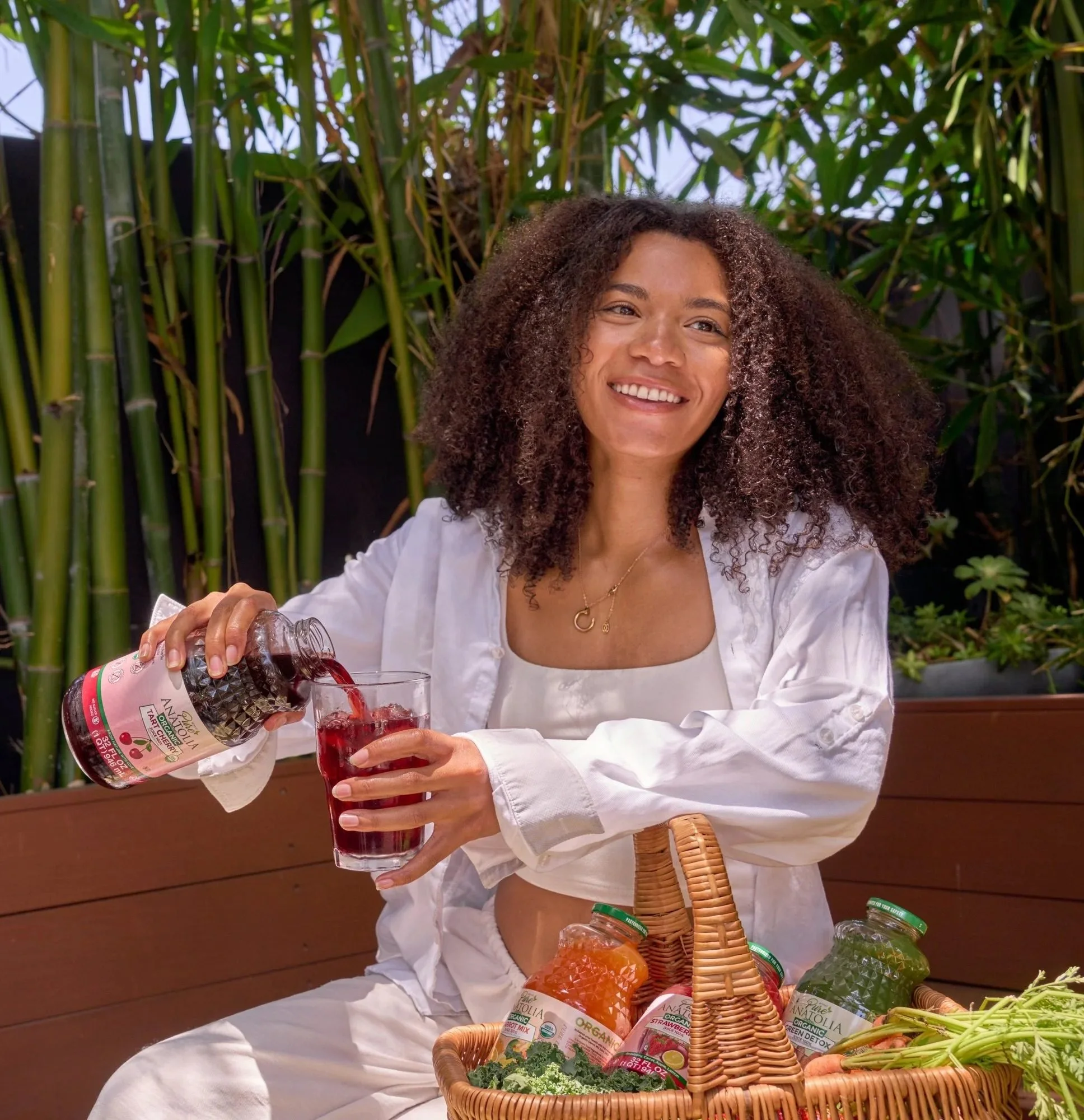 Woman pouring Pure Anatolia juice from a picnic basket in a garden, CPG lifestyle photography