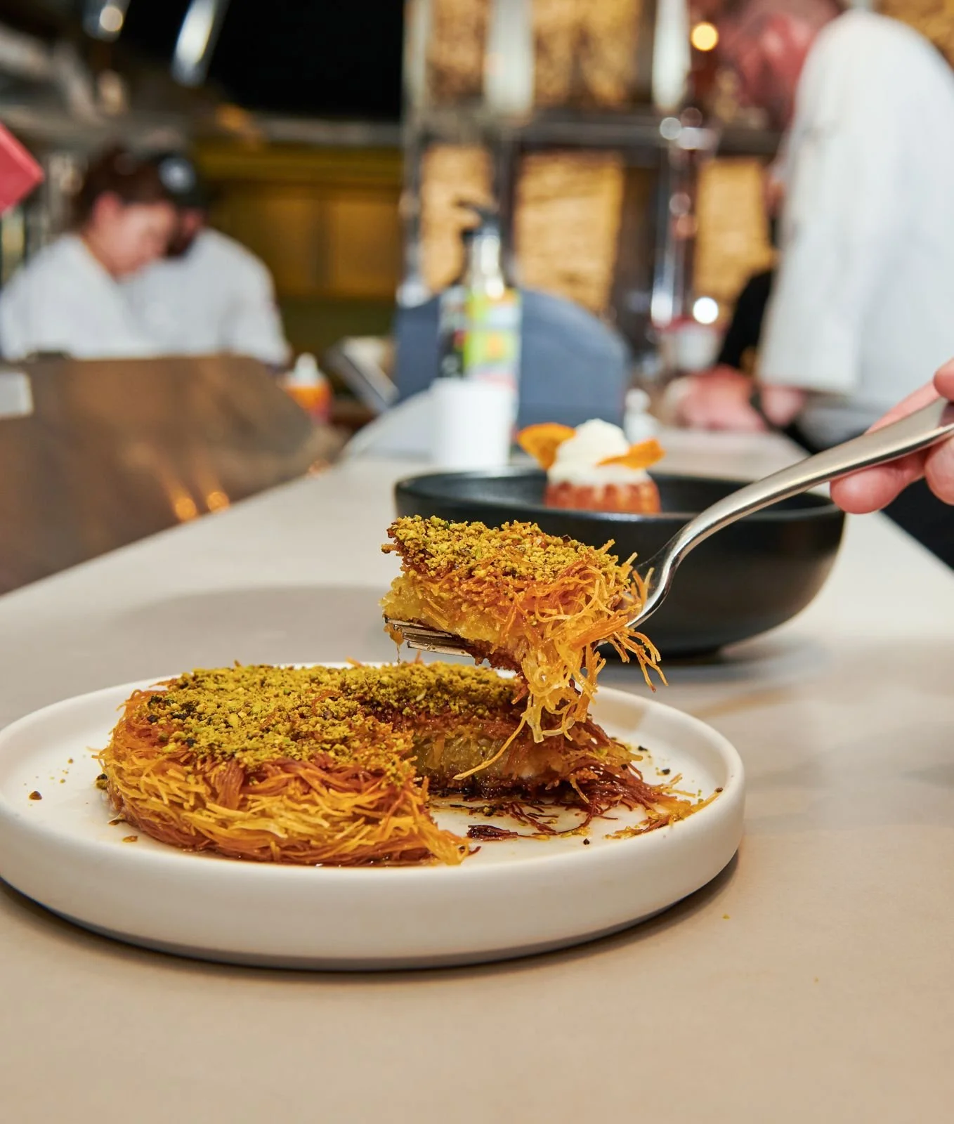 Chef plating a crispy potato dish at the pass