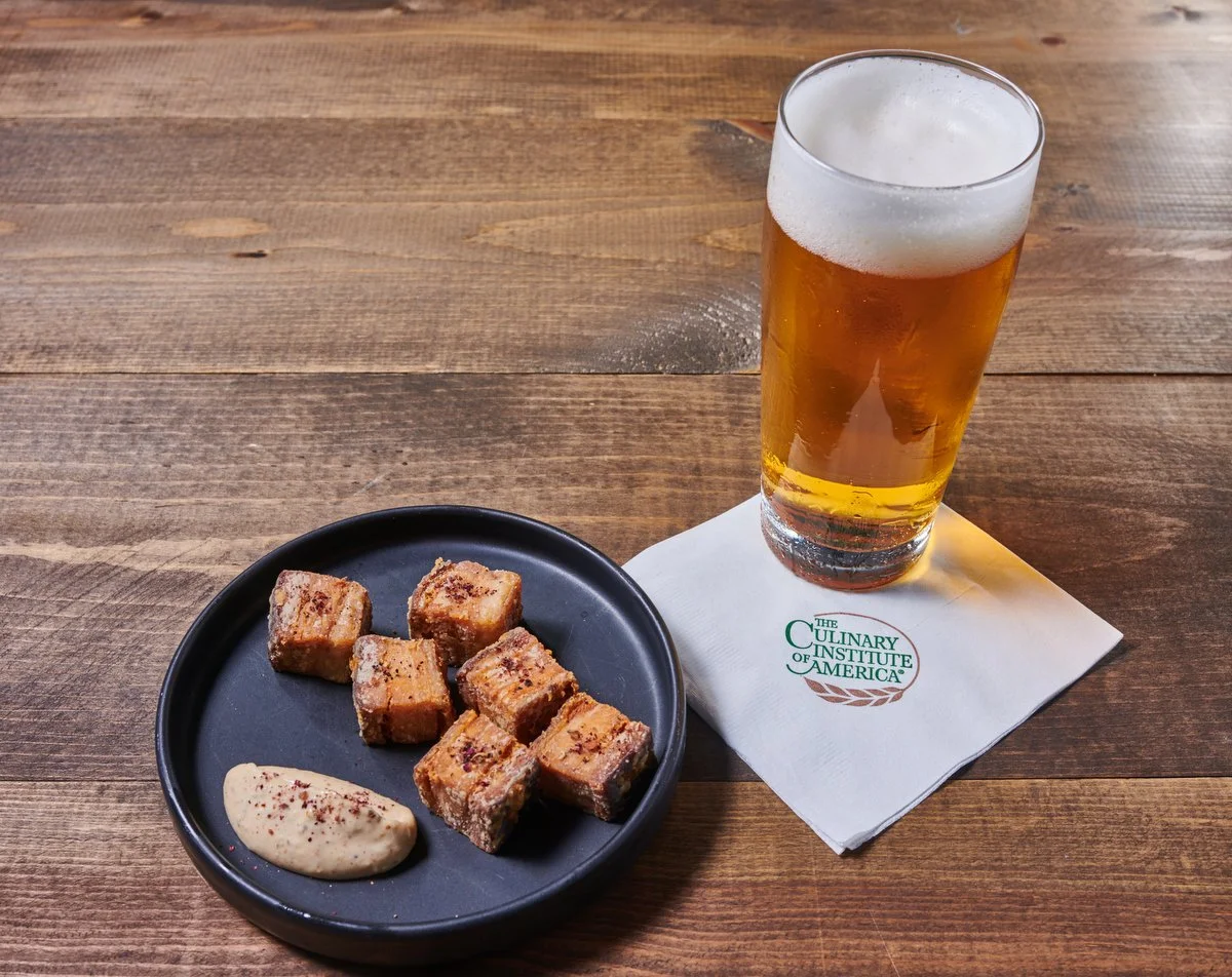 Glass of beer with fried bites on a wood board