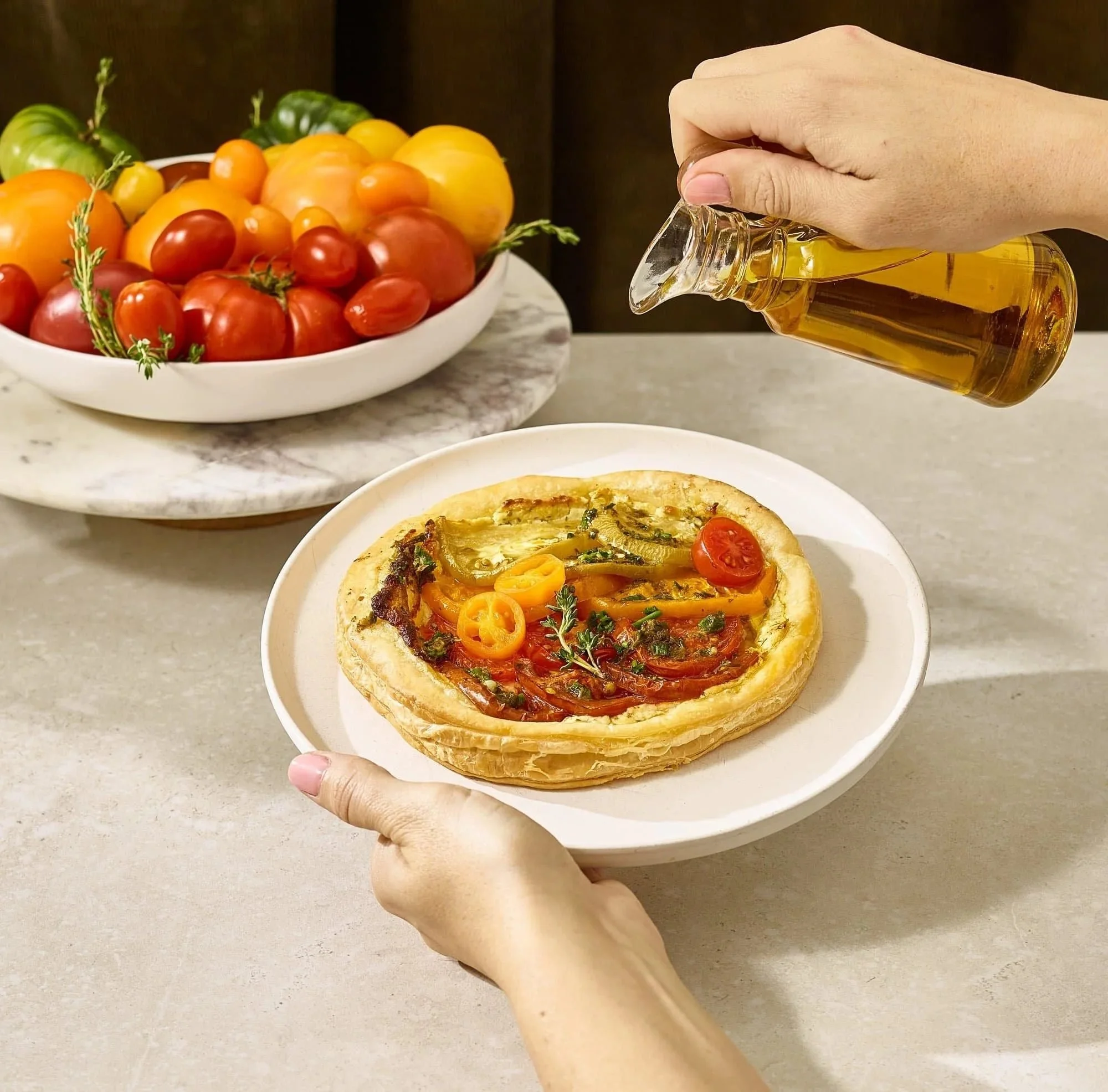Olive oil pouring over a tomato tart. Action food photography for oil and produce brands.