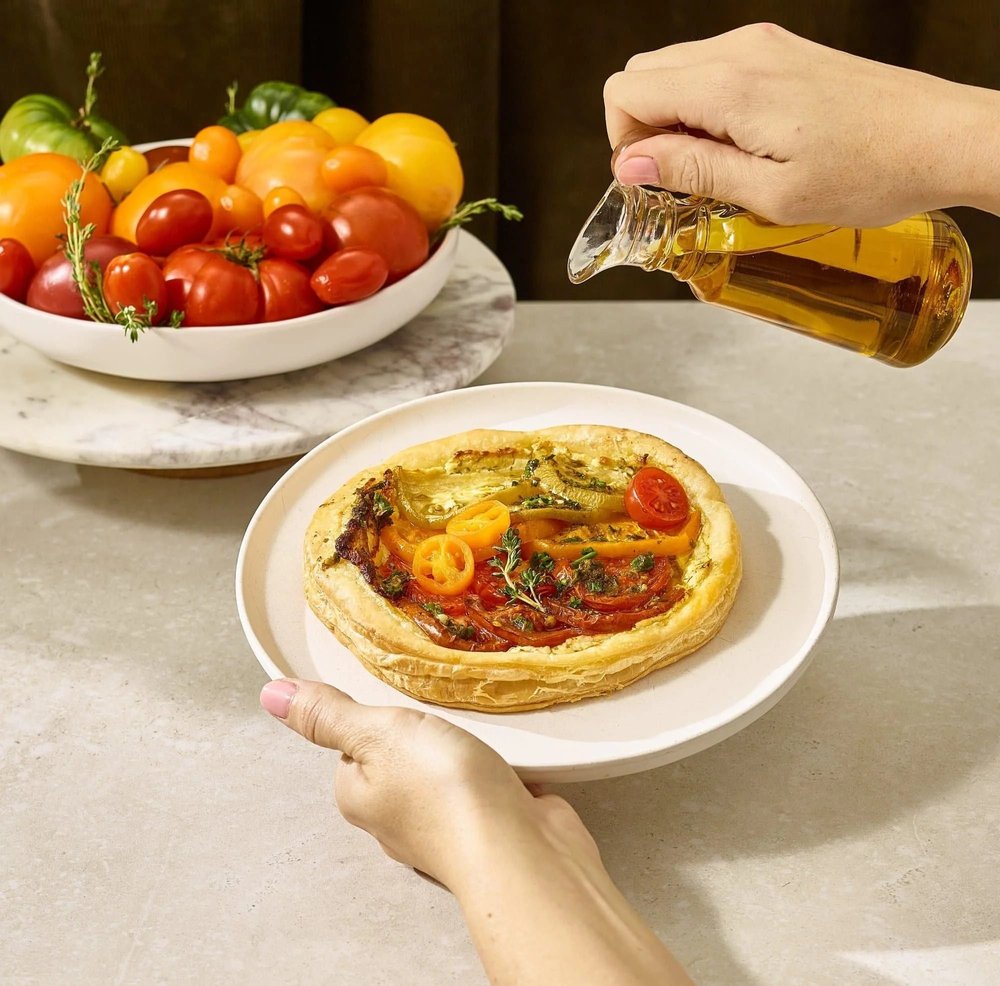 Olive oil pouring over a tomato tart. Action food photography for oil and produce brands.