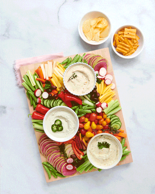 Hand dipping vegetables into dips on a crudite board, food stop motion