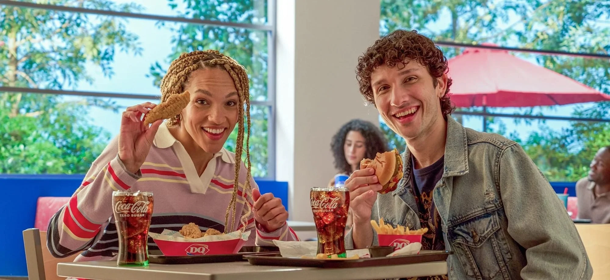 Two friends laughing over Dairy Queen treats in a booth, restaurant lifestyle photography