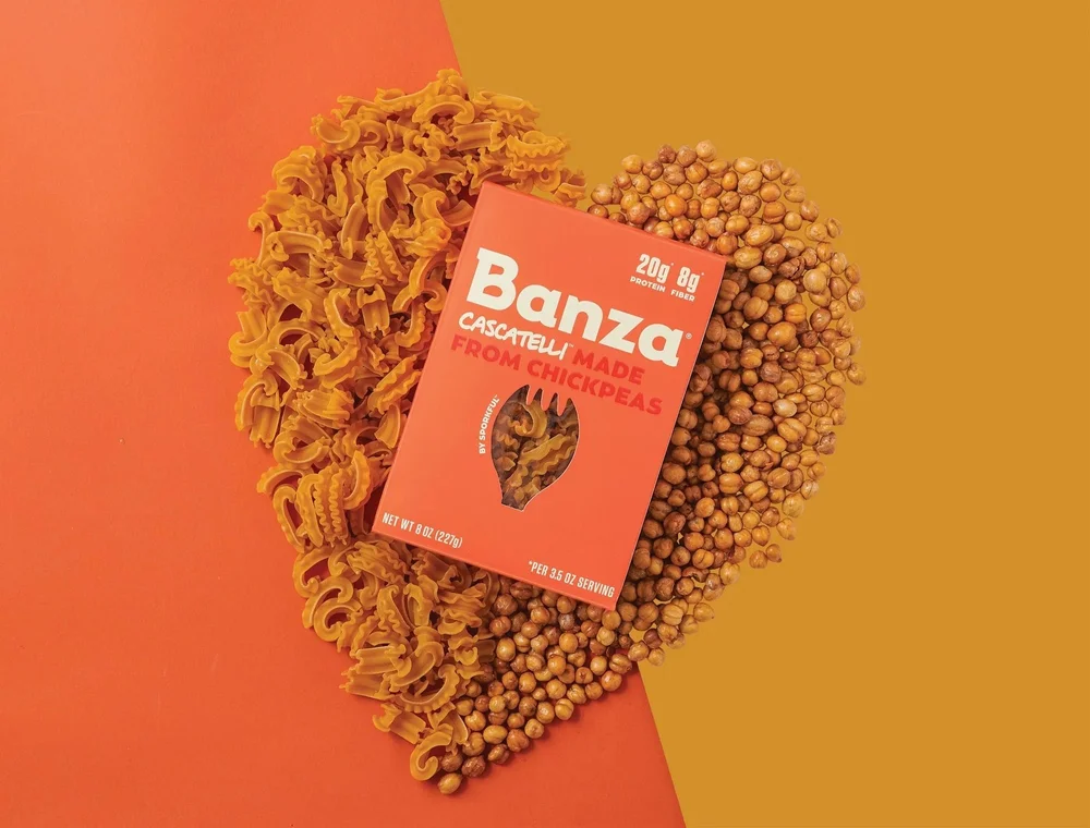 Chickpea pasta box styled in a heart of pasta on orange and mustard, creative packaging photography