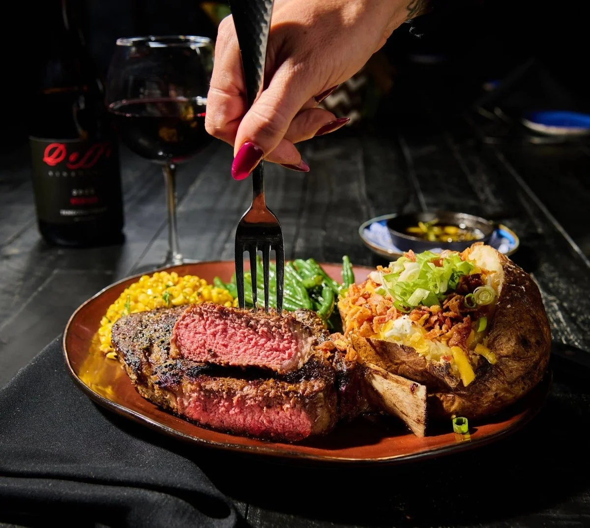 Steak with a baked potato and fork on a restaurant plate