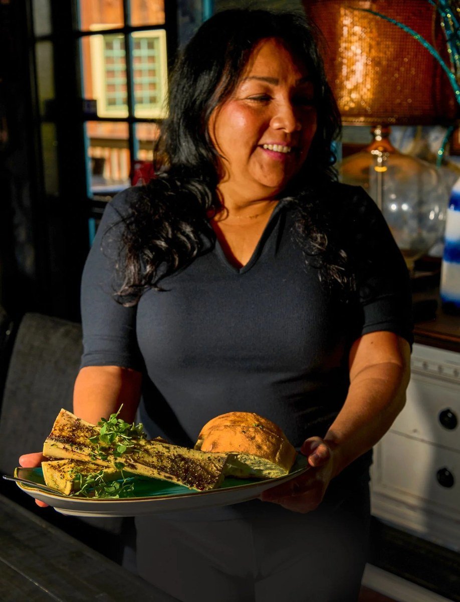 Server holding a plate of roasted bone marrow