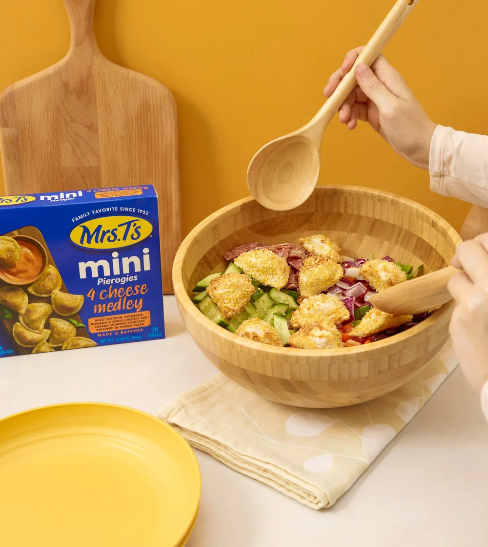 Mrs. T's mini pierogies in a salad bowl with the package. CPG frozen food photography with the product in use.