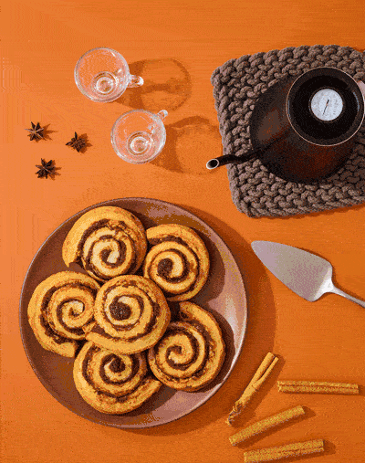 Stop motion GIF of icing spreading on cinnamon rolls. Animated bakery content.