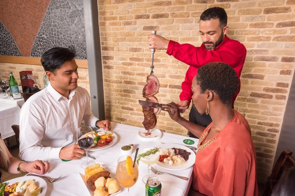 Server carving meat tableside for restaurant guests
