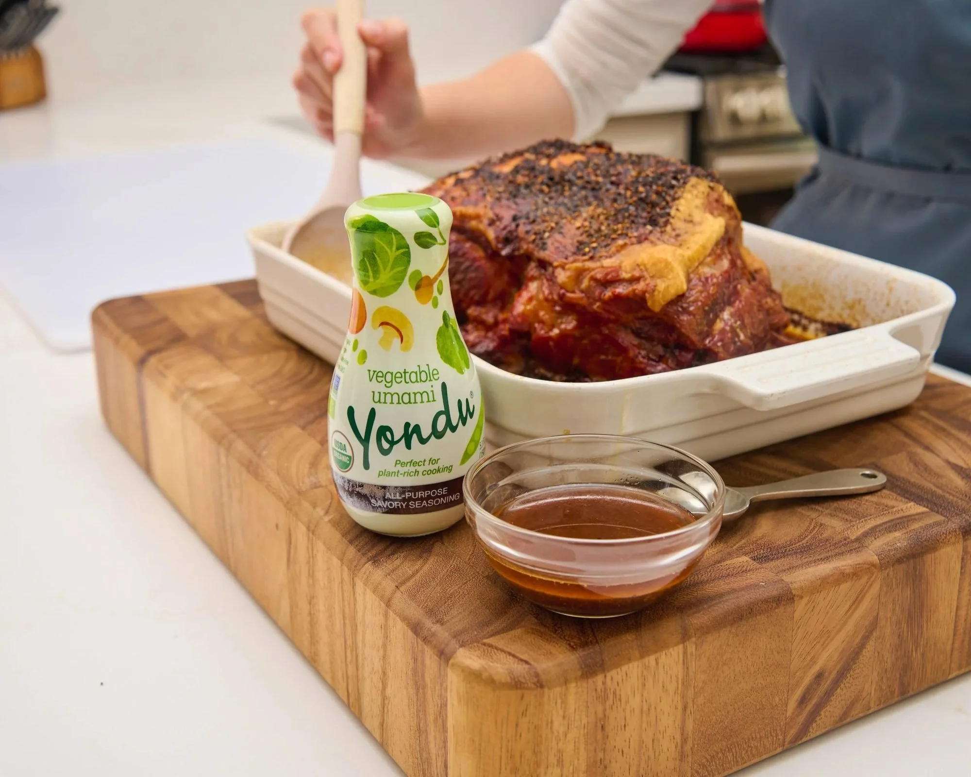 Sauce pouring over a sliced roast on a wooden board. Action food photography for sauce and marinade brands.