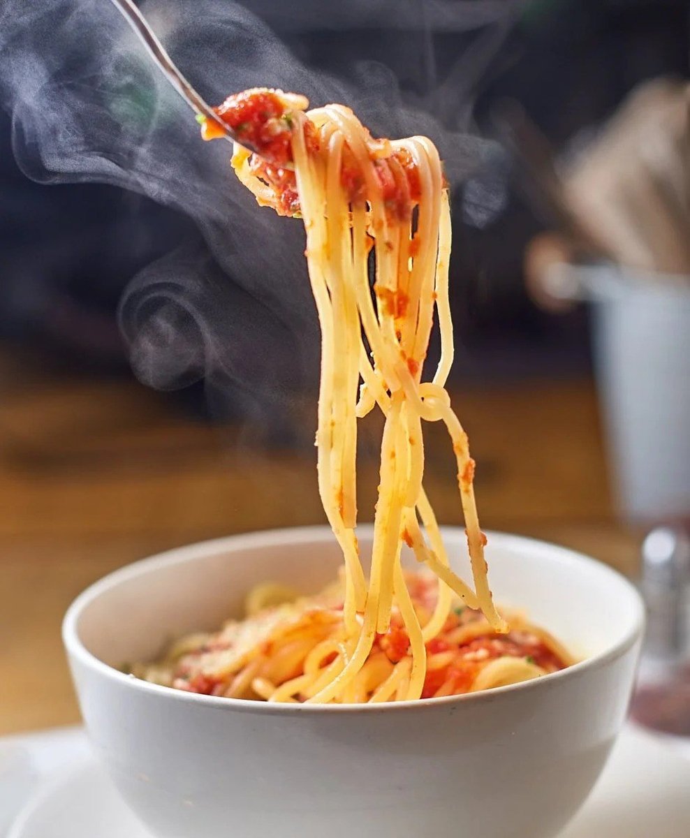 Spaghetti twirled on a fork above a steaming bowl