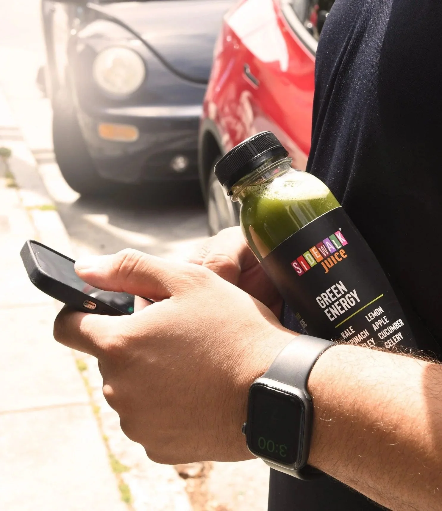 Man holding a green juice bottle and phone on the street, CPG beverage lifestyle photography
