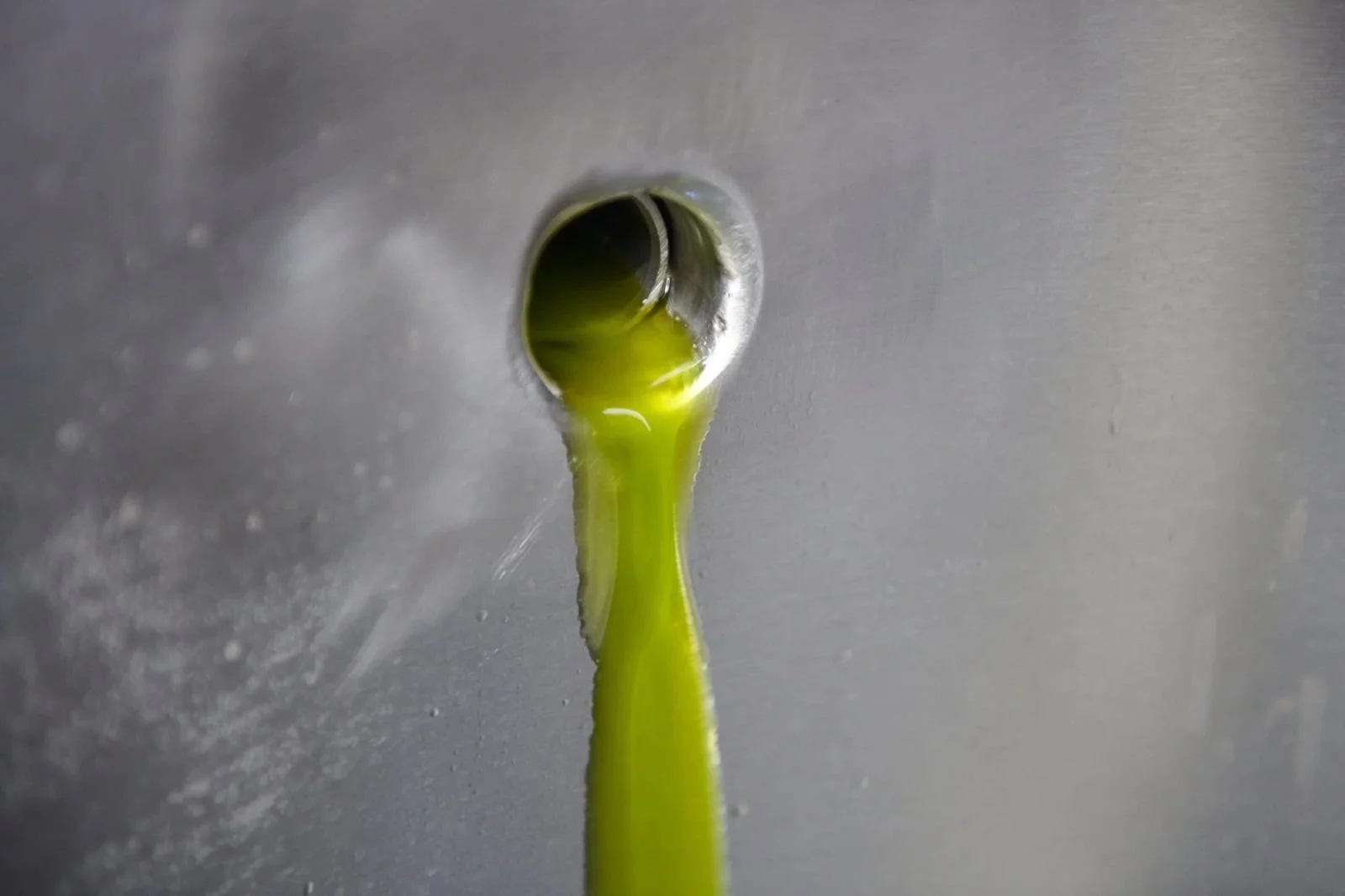 Fresh green olive oil pouring from the mill