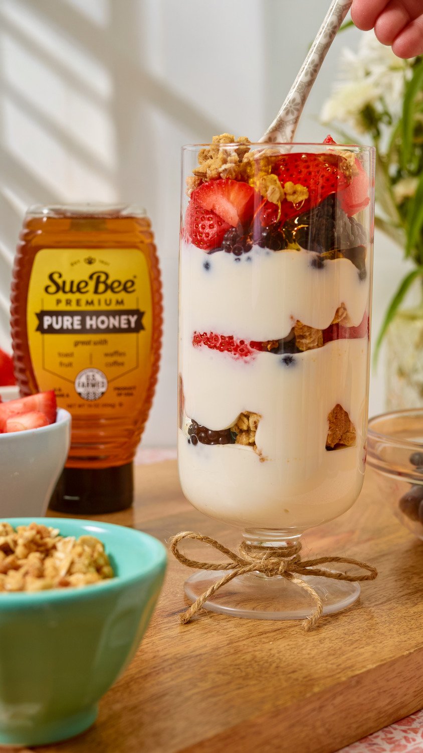 Yogurt and fruit parfait drizzled with Sue Bee honey. Breakfast recipe photography for a honey brand.