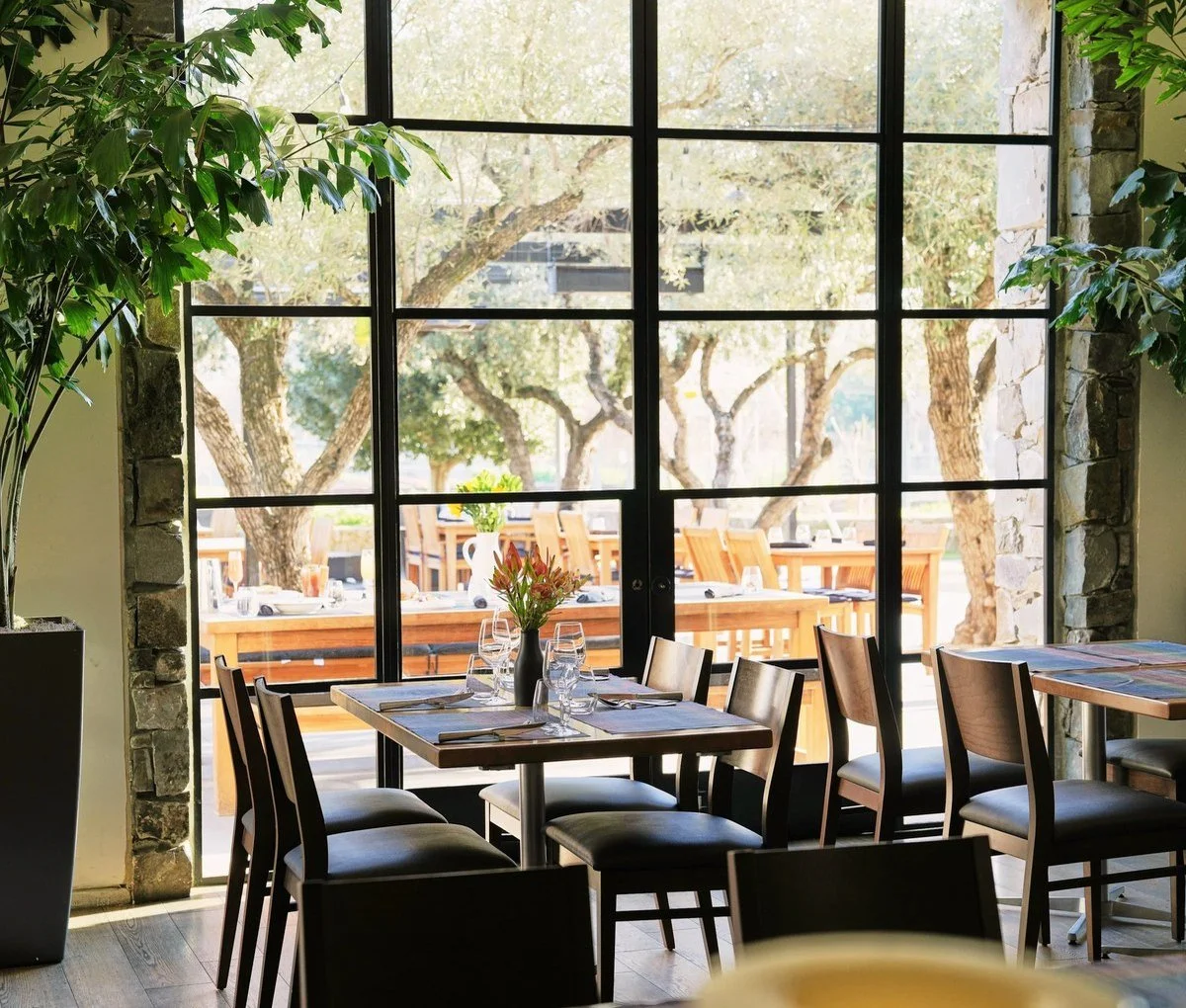 Bright restaurant dining room with floor to ceiling windows and set tables