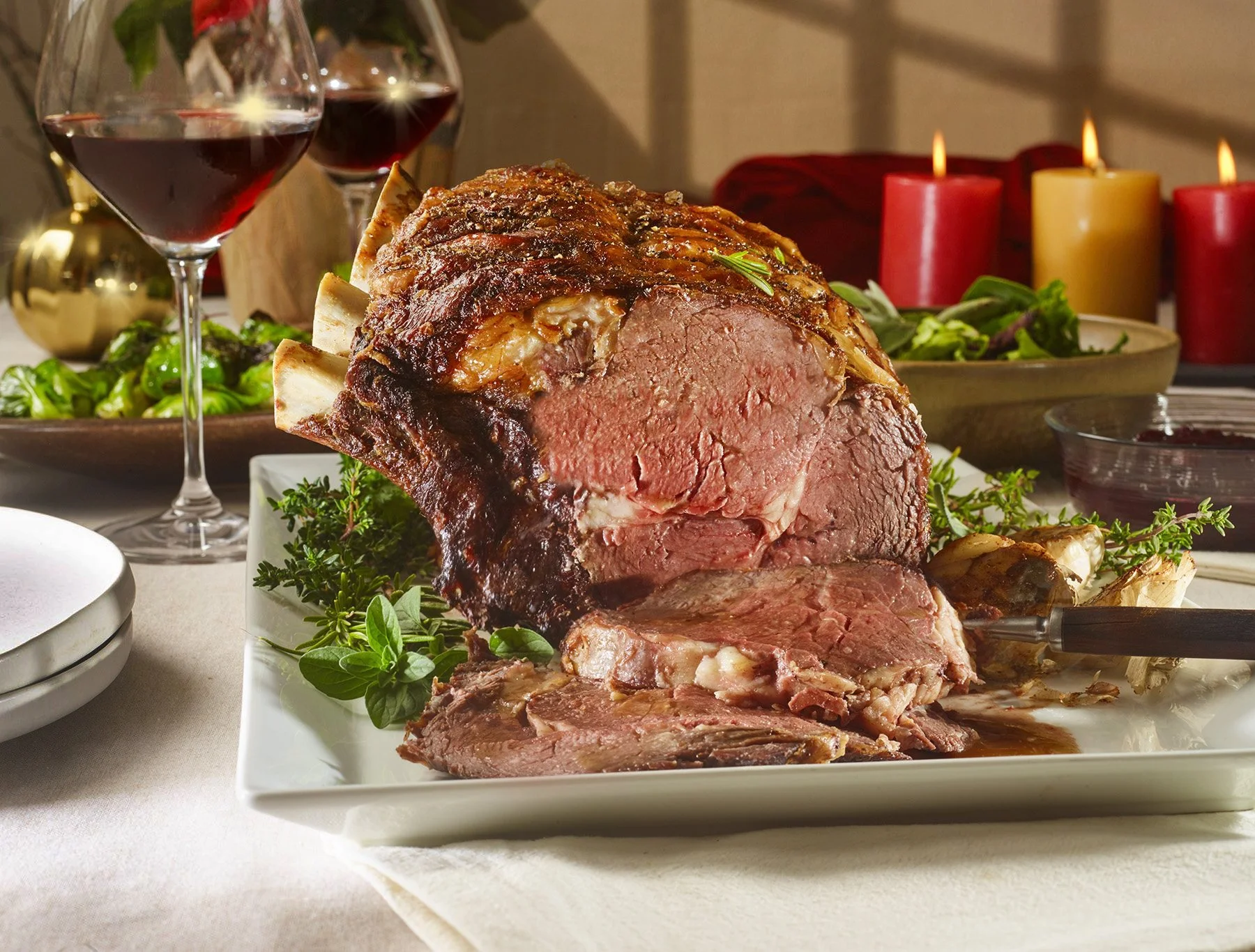 Holiday prime rib roast on a Christmas table with candles. Holiday meat and recipe photography for retail and brand campaigns.