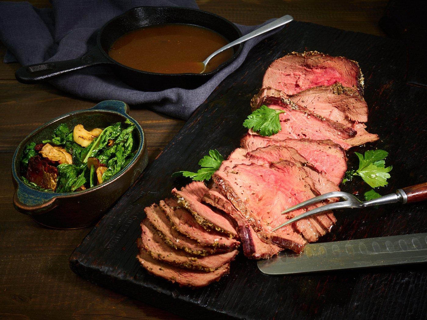 Food styling: carved roast beef on a dark board with gravy