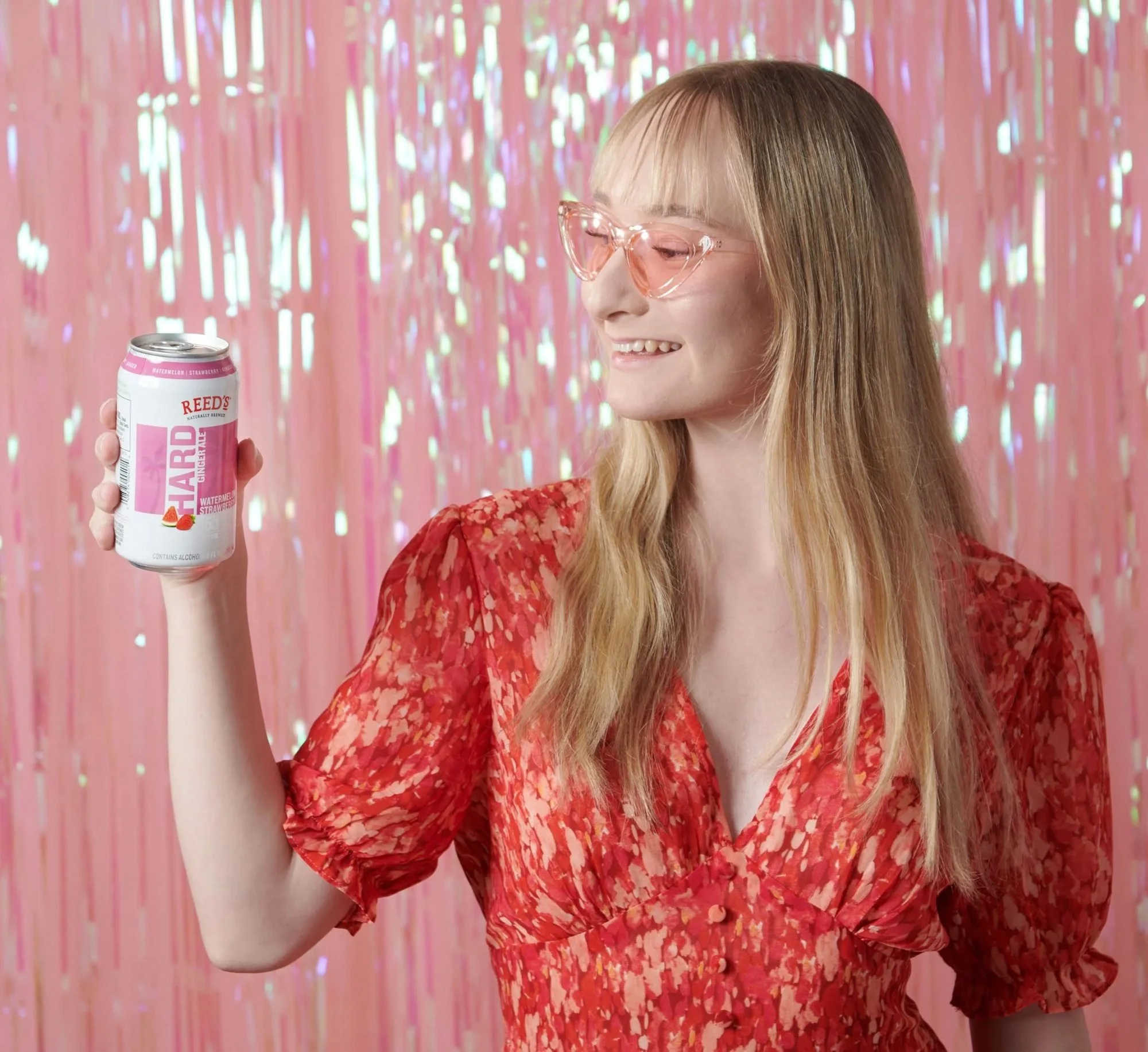 Model holding a pink sparkling can in front of pink tinsel, CPG beverage lifestyle photography