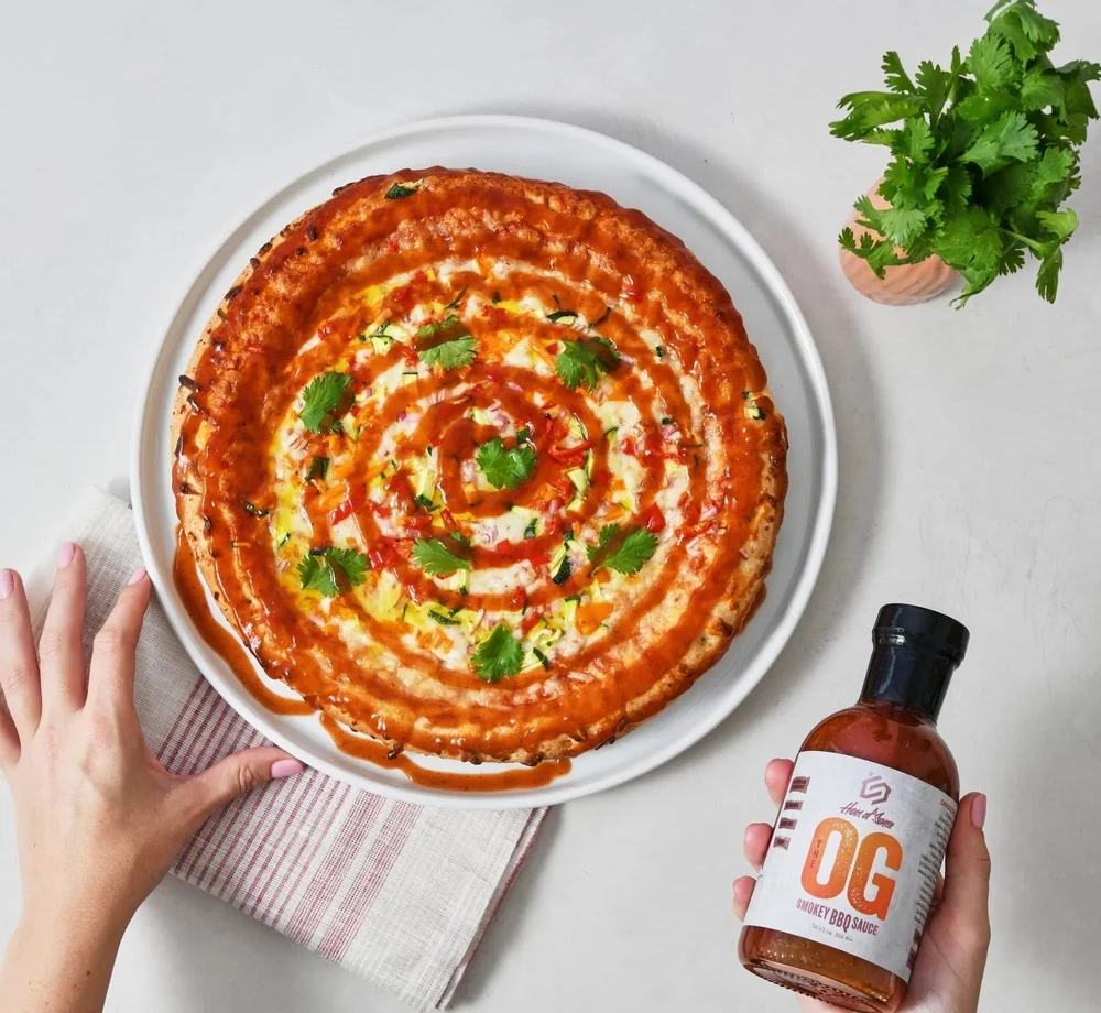Pizza with a swirl of OG sauce next to the sauce bottle. CPG sauce product photography with the finished dish.