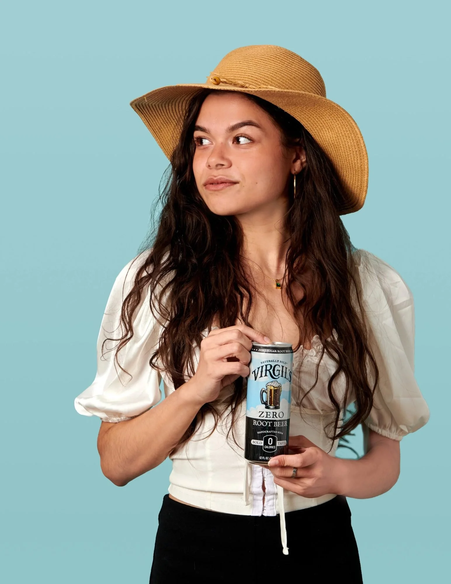 Model in a sun hat holding a can on blue, CPG beverage lifestyle photography
