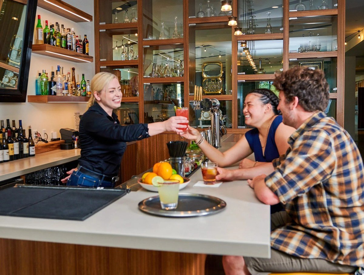 Bartender handing a drink across the kitchen bar