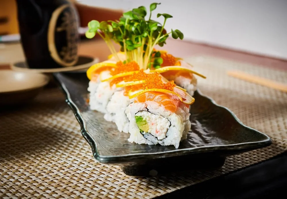 Sushi rolls with toppings on a black slate. Restaurant and Asian food photography.