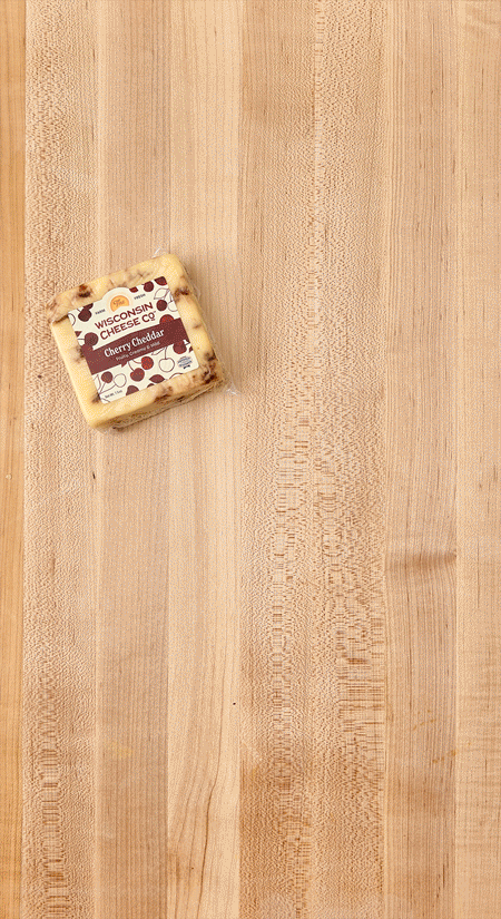 A small block of Wisconsin cheese with cherry and cheddar flavor on a wooden surface.