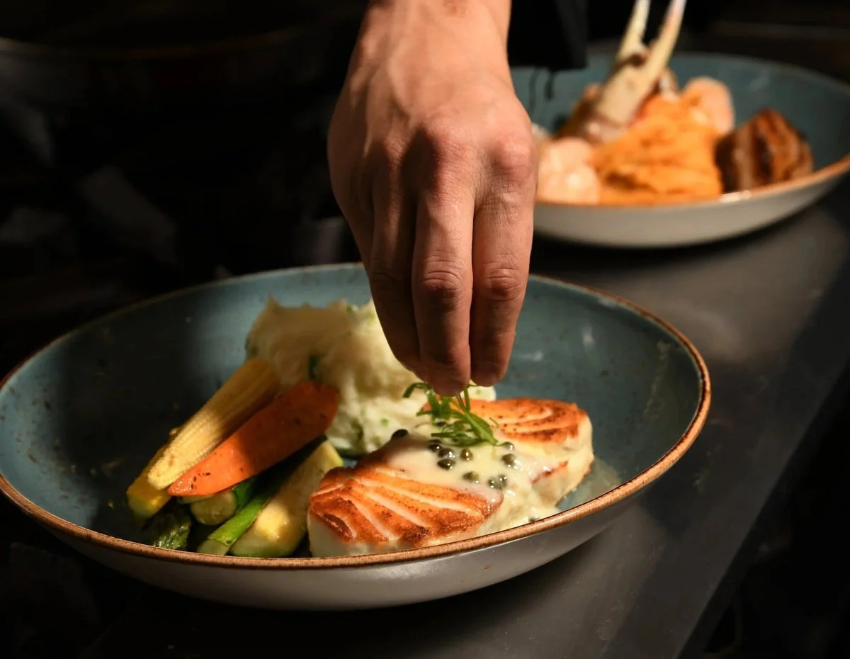 Chef garnishing a salmon dish by hand