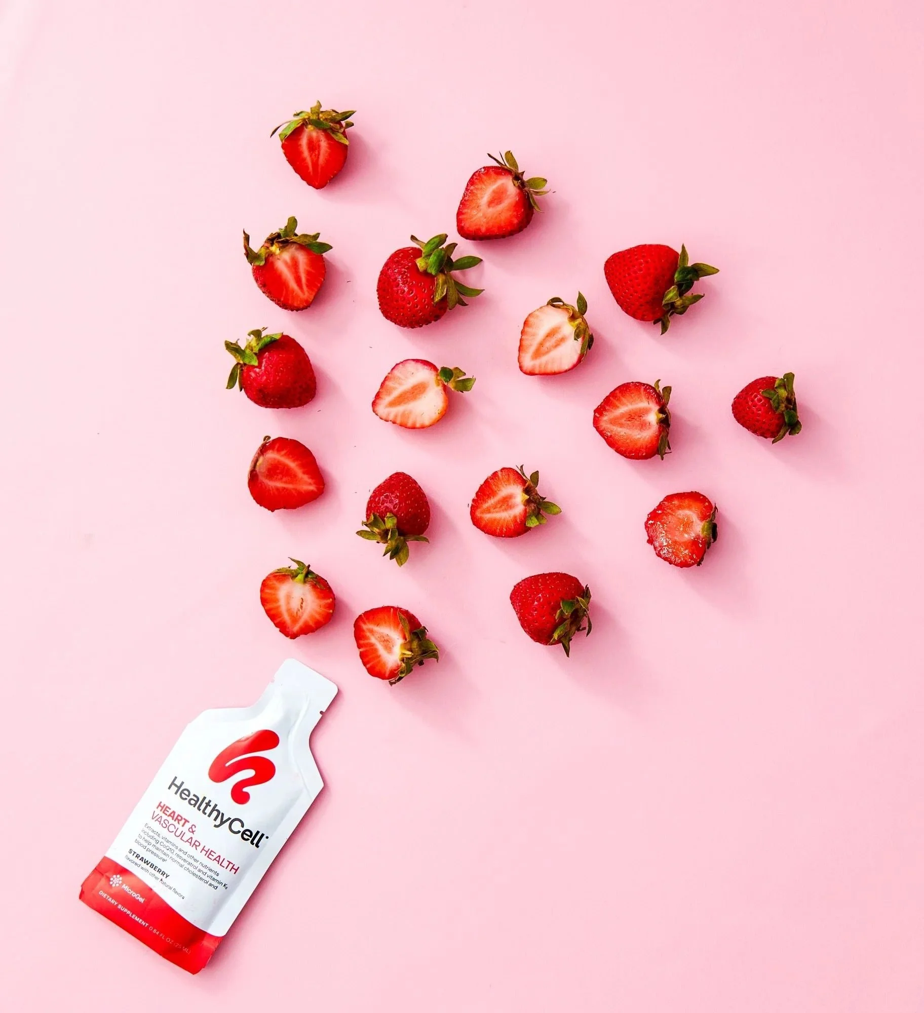 Healthy Cell gel supplement packet with strawberries on pink, CPG supplement photography