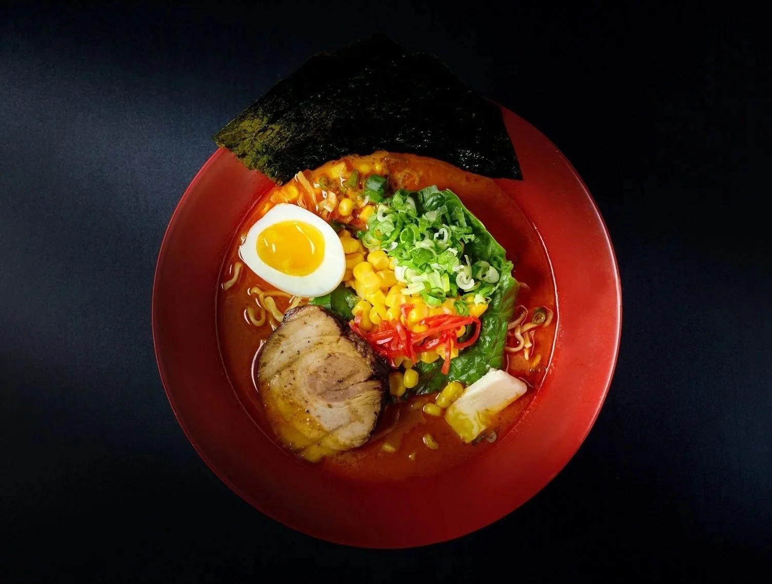 Food styling: ramen bowl with soft egg and scallions on a dark background