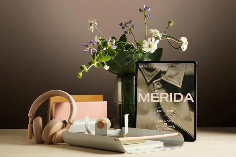 A tablet, headphones, flowers, and office supplies on a desk.