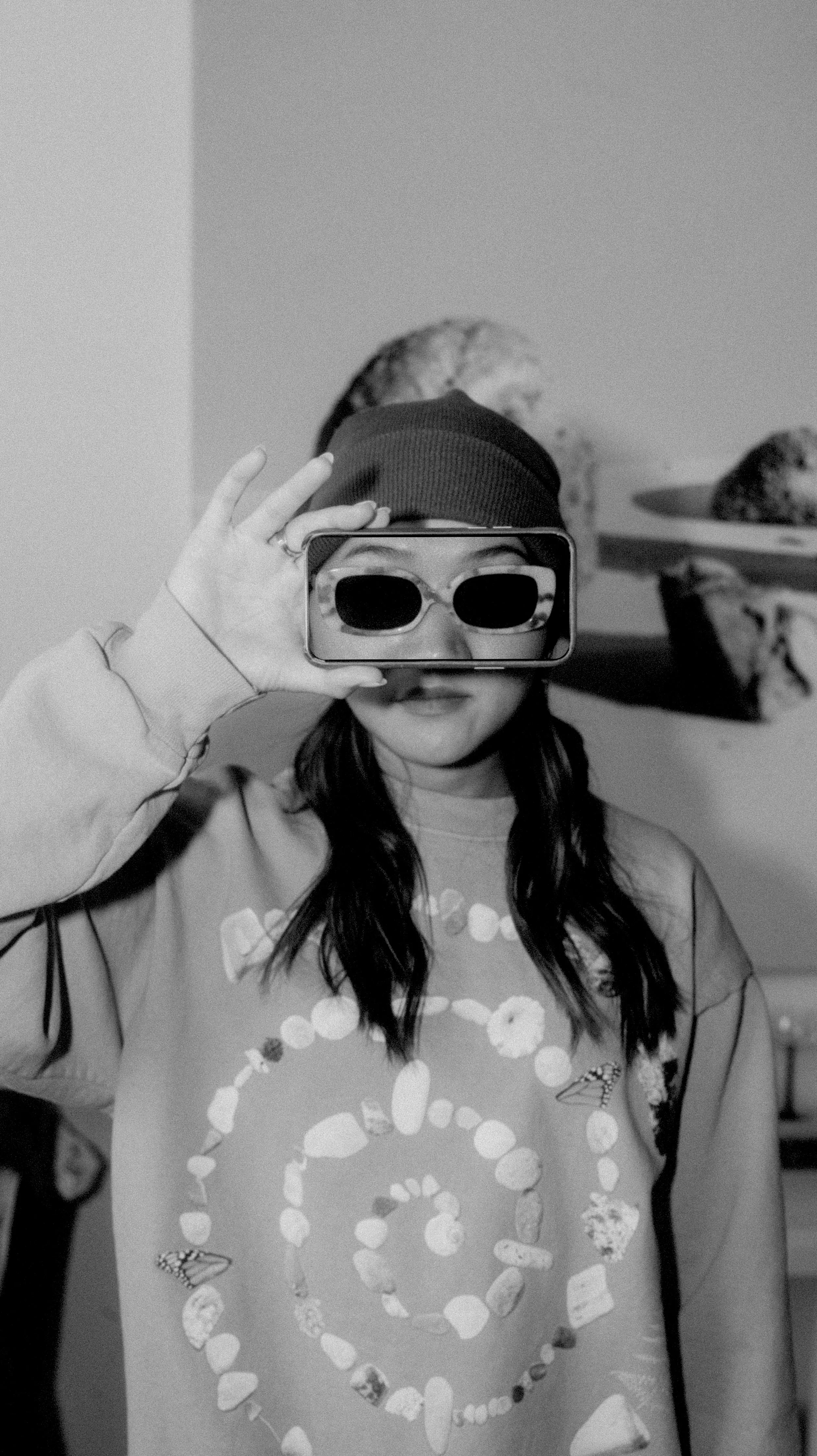 Mindy Nguyen holding up a smartphone to her face in a black and white headshot